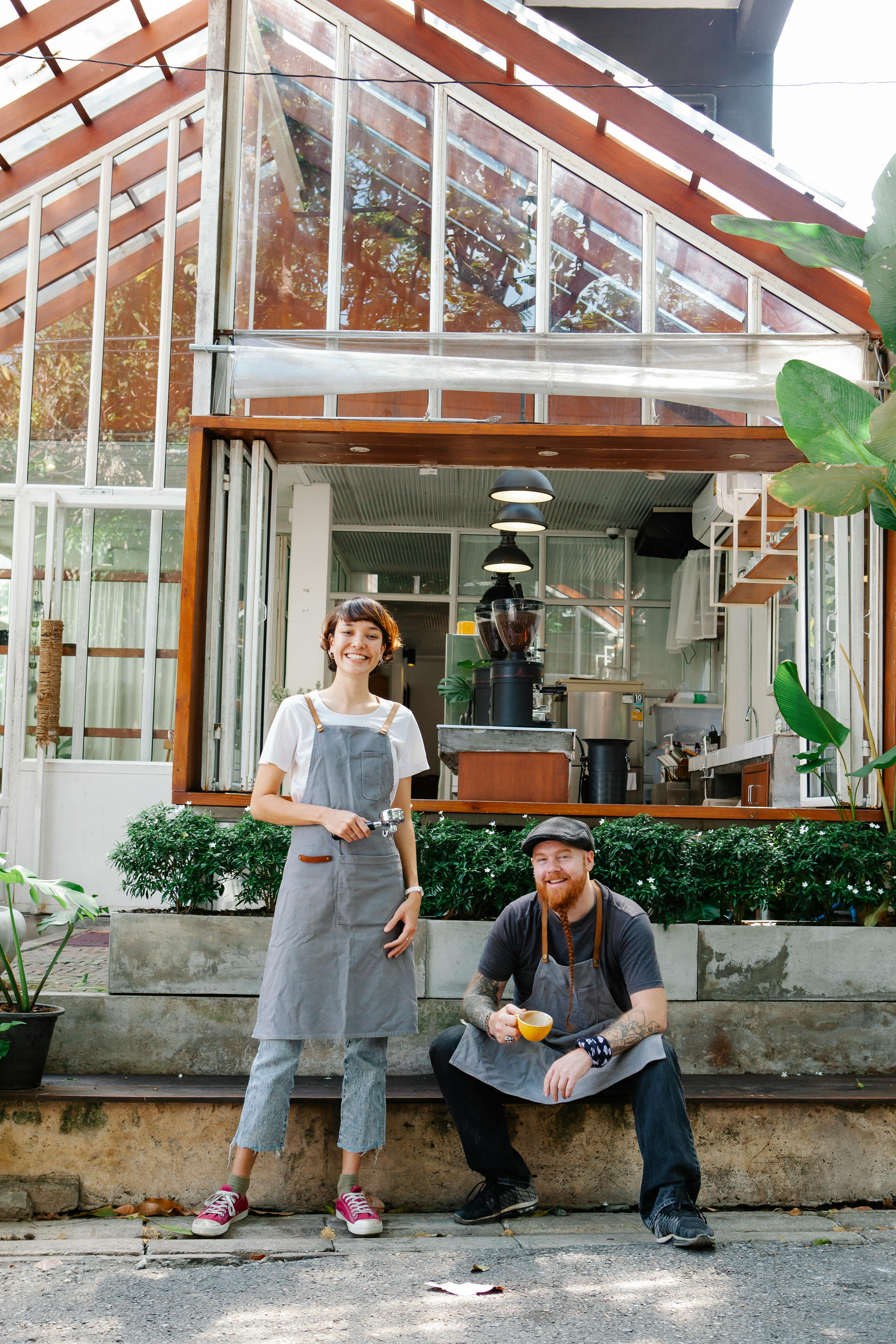 Two young servers smiling outside a café | Source: Pexels