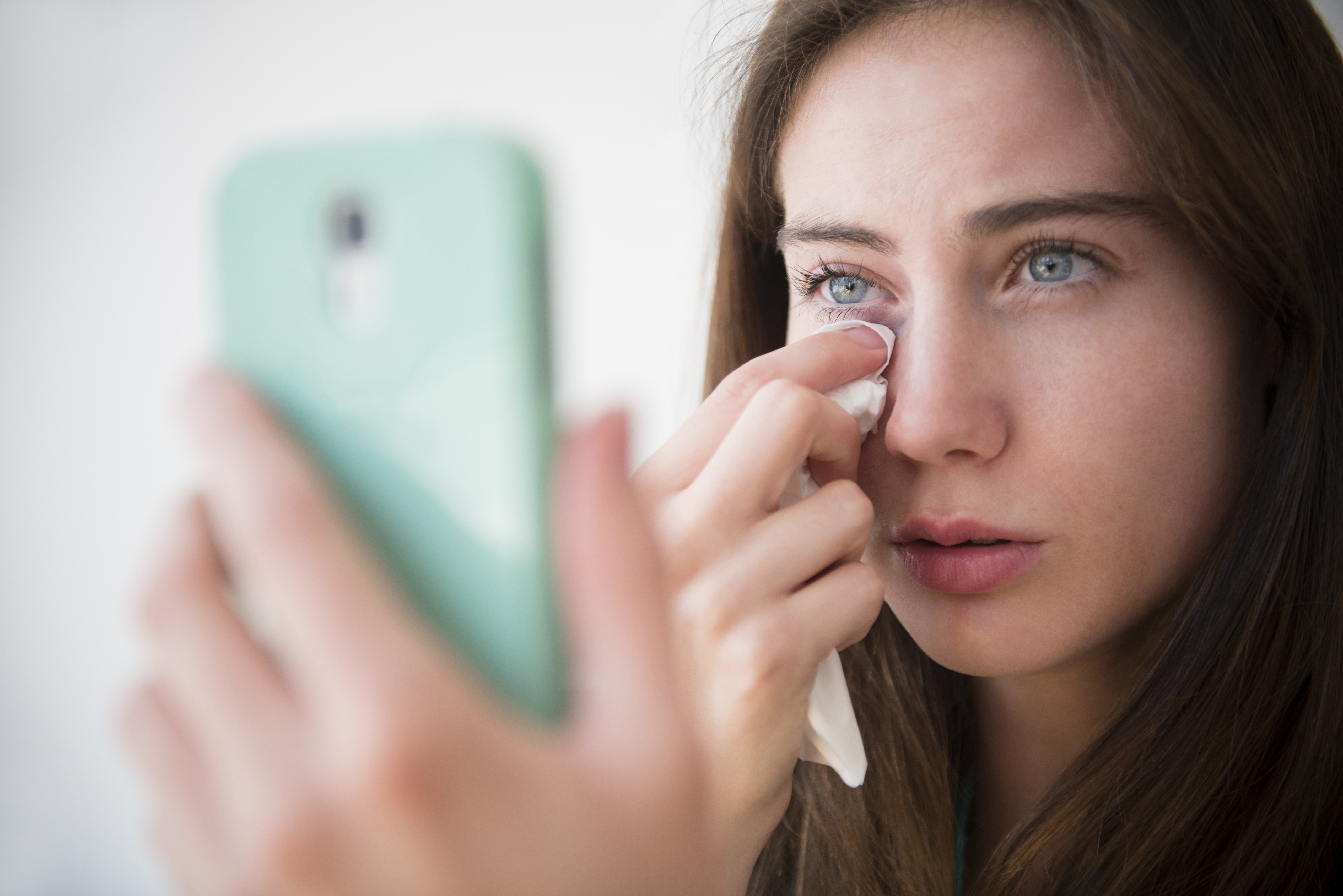 A woman wiping away tears while on a phone call | Source: Getty Images