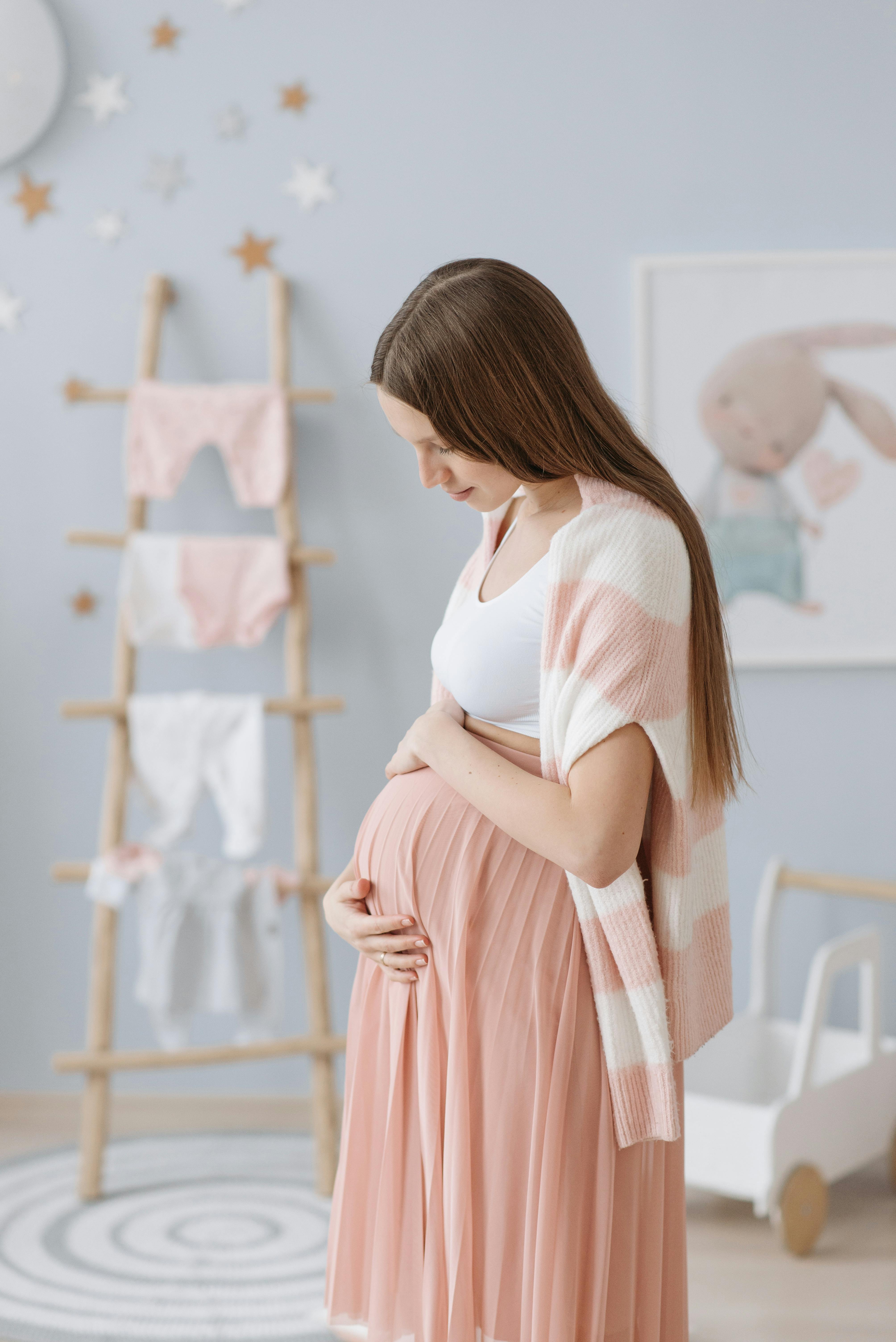 A woman smiling at her belly | Source: Pexels