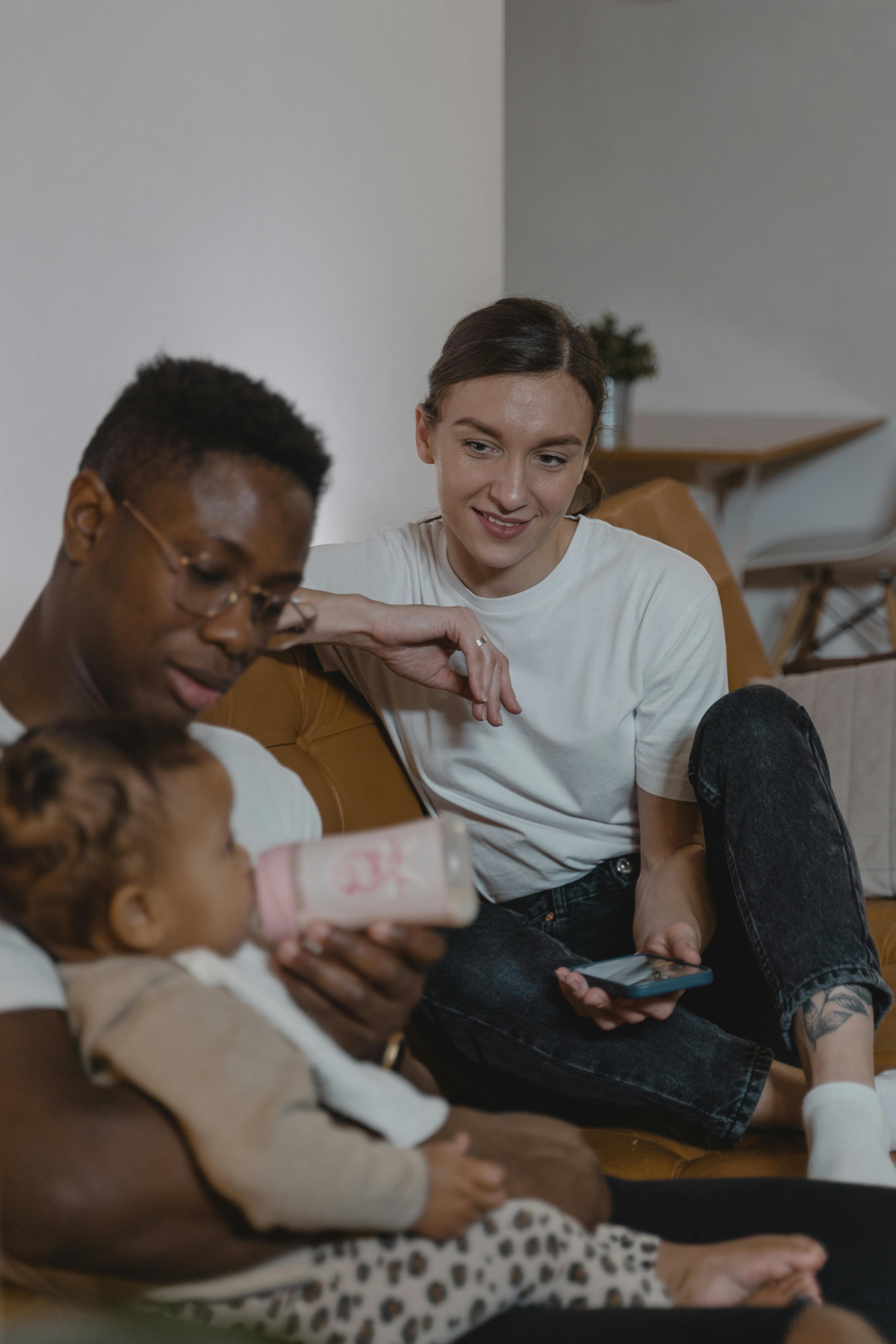 A dad feeding his baby while the mom looks on | Source: Pexels